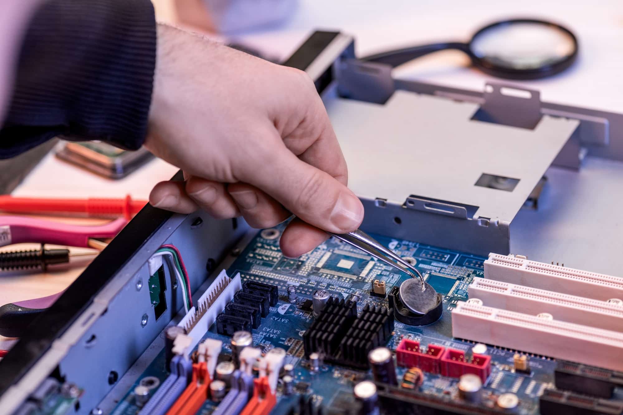 Teknisi Haris'Com sedang memeriksa dan memperbaiki motherboard komputer